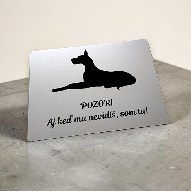 Stříbrná tabulka s ležící německou dogou a nápisem I když mě nevidíš, jsem tu