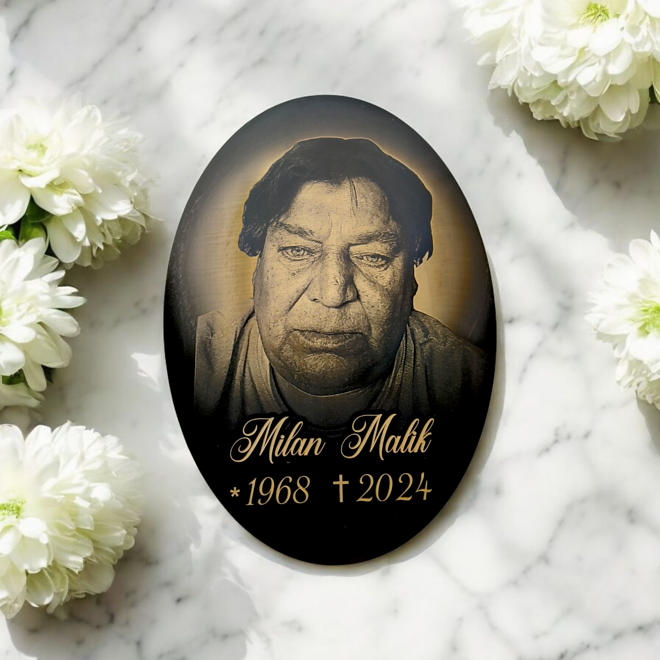 černá oválná tabulka na hrob s fotografií na mramoru s květinami
